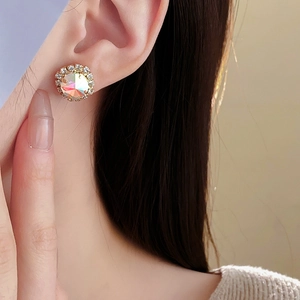 Close-up of model wearing gold round stud earrings with colorful zircon and small diamonds