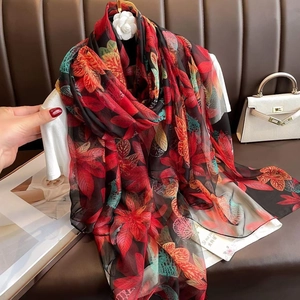 Detailed texture of lightweight maple leaf print long scarf on a leather surface