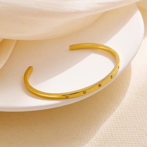 Detail of 18k gold plated stainless steel cuff bracelet with five inlaid crystals