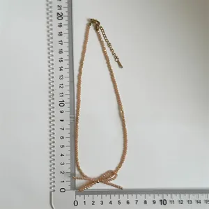 Detailed measurement of light pink beaded bow necklace with golden adjustable chain