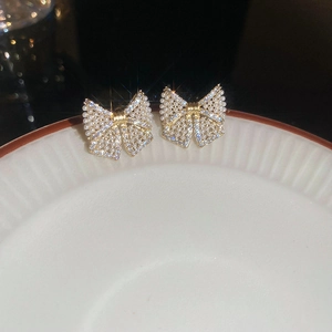 Macro shot of bow earrings with sparkling cubic zirconia and pearls on a ceramic plate