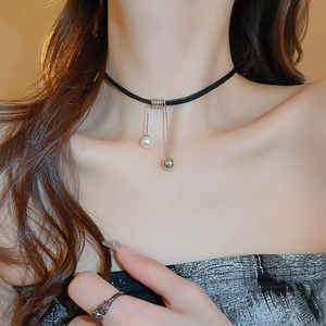 Close-up of black leather choker necklace with silver chains, pearl and metal ball pendants
