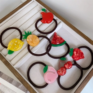 Detail of colorful resin fruit hair ties including lemon and watermelon on a white tray