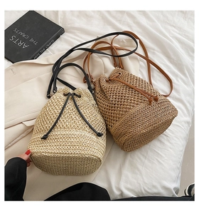 Detailed view of beige and khaki woven paper straw bucket bags with leather drawstring straps