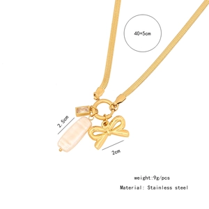 Detail of gold snake chain necklace with bow, pearl and crystal charms in stainless steel