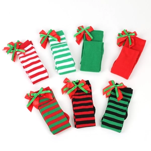Flat lay of colorful Christmas over-knee socks featuring stripes and festive bow details