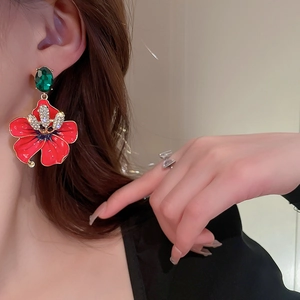Elegant floral drop earrings with red petals, green gemstone studs, and sparkling rhinestones