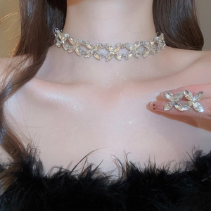 Close-up of elegant leaf-shaped crystal necklace and ring set on a model in black