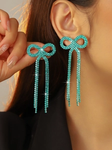 Macro detail of turquoise bow earrings with long tassels and sparkling rhinestones