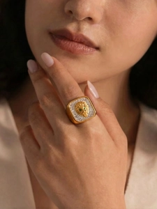 Close-up of a gold lion head ring with green stone eyes and shimmering white crystals