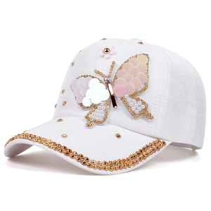 Détail de la casquette blanche en denim avec papillon en paillettes et strass dorés brillants