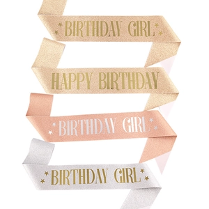 Close-up of sparkling birthday king sashes in champagne, rose gold, and silver finishes