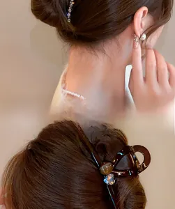 Detail of amber resin hair claw clip with blue heart crystals on brunette hair