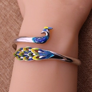 Detailed peacock cuff bracelet with blue enamel inlay and silver finish on burlap