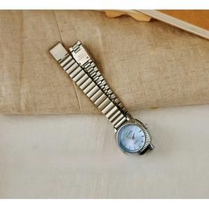Macro view of women's vintage steel watch featuring a light blue sunray dial and fluted bezel