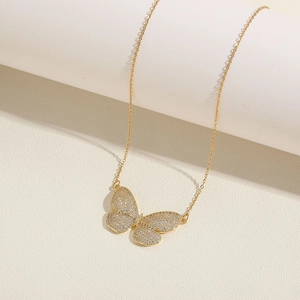 Close-up of golden butterfly necklace with pavé-set zircons and elegant fine chain
