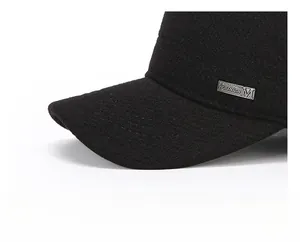 Detail of thickened brim and metal Fashion M logo on black wool-like flat cap
