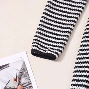 Gros plan sur la maille texturée et les manches à rayures noires et blanches de la robe