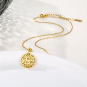 Detailed close-up of golden round letter E pendant necklace with beaded border and fine chain