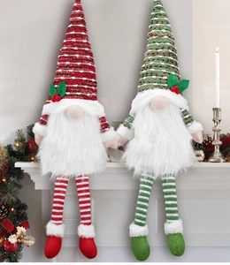 Close-up of two long-legged Christmas gnomes sitting on a mantel with festive lighting