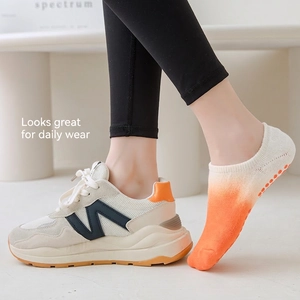 Non-slip Pilates yoga socks with orange gradient and silicone grips shown on model
