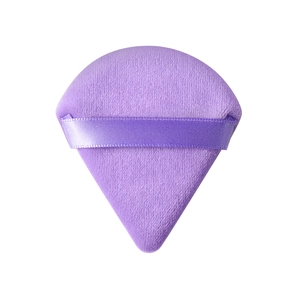 Vista macro de borla de maquillaje violeta con superficie aterciopelada y cinta de raso