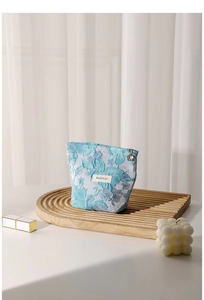 Close-up of light blue floral jacquard makeup bag with a decorative flower zipper puller