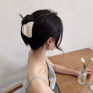 Macro shot of large cream acetate hair claw clip styling a chic French bun updo