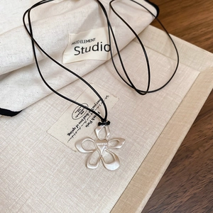 Detailed macro view of matte silver hollow flower pendant with a black cord necklace