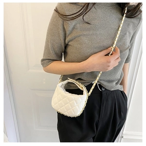 Detailed view of a white quilted mini bag with a gold chain strap worn by a model