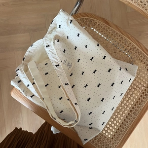 Detail of floral canvas tote bag with black bows on a rustic wooden chair backdrop