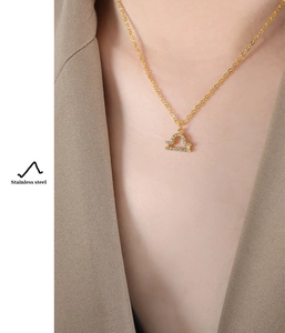 Detailed view of a gold Libra constellation pendant with pavé cubic zirconia on a thin chain
