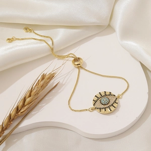 Macro view of adjustable gold evil eye bracelet with blue and white pavé crystals