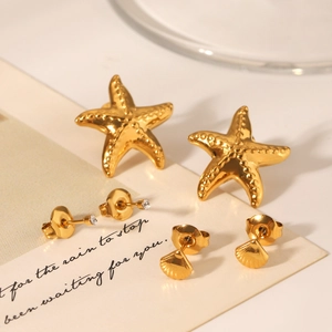 Détail de trois paires de boucles d'oreilles dorées étoile de mer et coquillage avec zircon