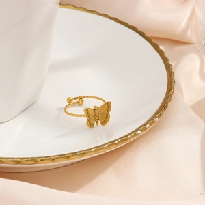 Close-up of golden butterfly open ring with textured details on elegant ceramic tray