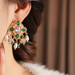 Gros plan de boucles d'oreilles vintage en perles et diamants avec accents d'émeraude