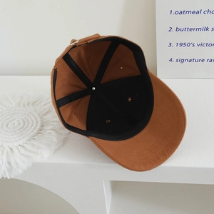 Detail view of brown cotton baseball cap interior showing black lining and metal buckle