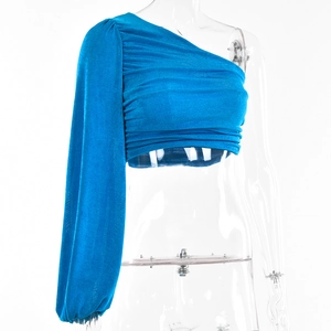 Détail du haut bleu à une épaule et manches longues avec tissu froncé et coupe ajustée