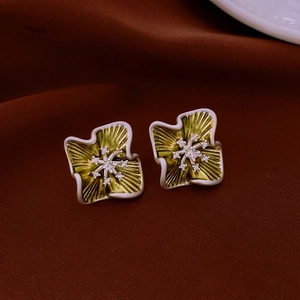 Dettaglio macro di orecchini a fiore in argento con smalto giallo-verde e zircone lucido