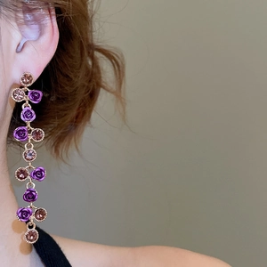 Detail of elegant silver needle earrings with purple rose pendant and sparkling rhinestones