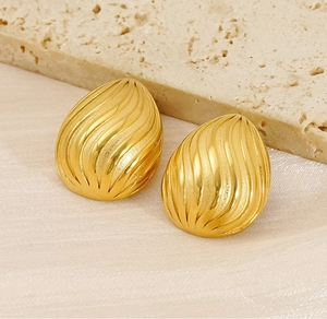 Macro view of gold-plated egg-shaped earrings with textured spiral vertical stripes