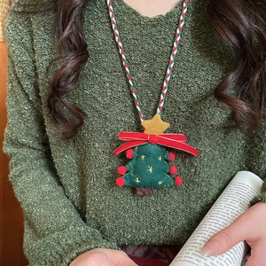 Detail of Christmas tree felt pendant necklace with red pom-poms and woven cord