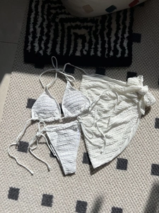 Detailed view of white three-piece seersucker bikini with matching textured sarong wrap