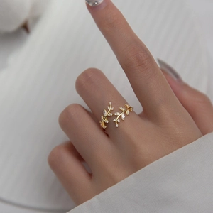Adjustable golden leaf branch ring with clear zircon crystals on model finger