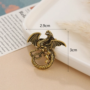 Vintage golden dragon brooch in coiled alloy design measuring 3cm by 2.9cm on ceramic tray