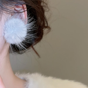 Détail d'une boucle d'oreille pompon gris clair à texture douce sur modèle