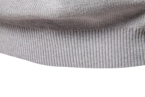Detailed close-up of the grey knitted sweater featuring ribbed hem and fine knit texture