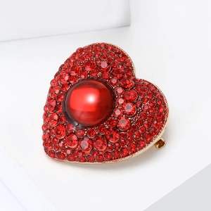 Detailed view of a heart-shaped brooch featuring vibrant red rhinestones and a central bead