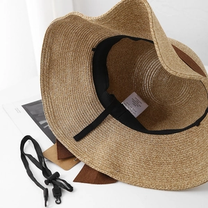 Detail view of straw sun hat interior with sweatband, wash label and windproof strap