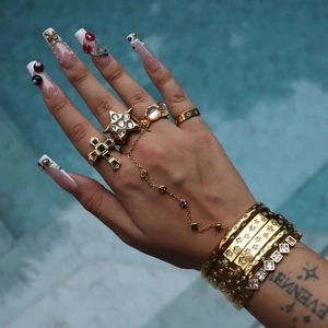 Detailed shot of gold plated star rings and green gemstone bracelet by the blue pool